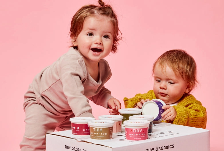 Two babies with a box of Tiny meals