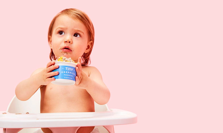 Smiling baby on high chair with Tiny meal